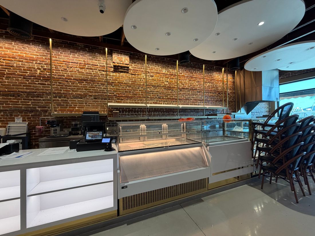 Pastry display case and track lighting on exposed brick wall in Tarpon Springs restaurant by At Your Service Electric